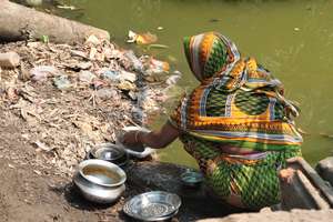 Woman washing dishes in the pond