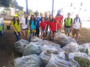 Volunteers pose near bags full of trash & weeds