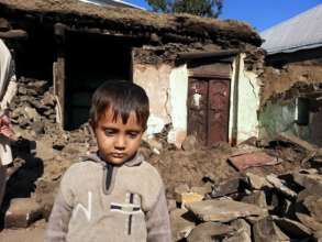 A Little Boys Stands In Front of His Damaged Home