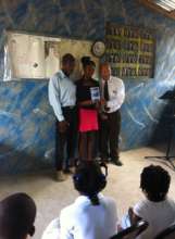 Milene receiving award with her father and teacher