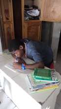Ysaac writing his name on his school books