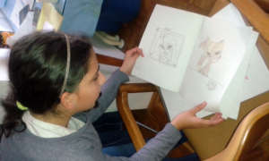 Ivana proudly shows a notebook of her drawings