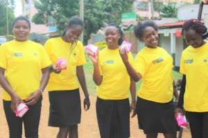 Some girls proudly holding  boxes of sanitary pads