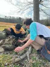 Counselor helping a camper to find bugs