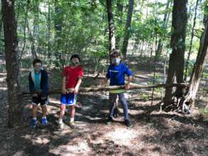 Josh, Jacob, and Aiden work on a shelter together.