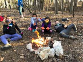 Violet, Elise, Carmen, and Logan warm up by a fire