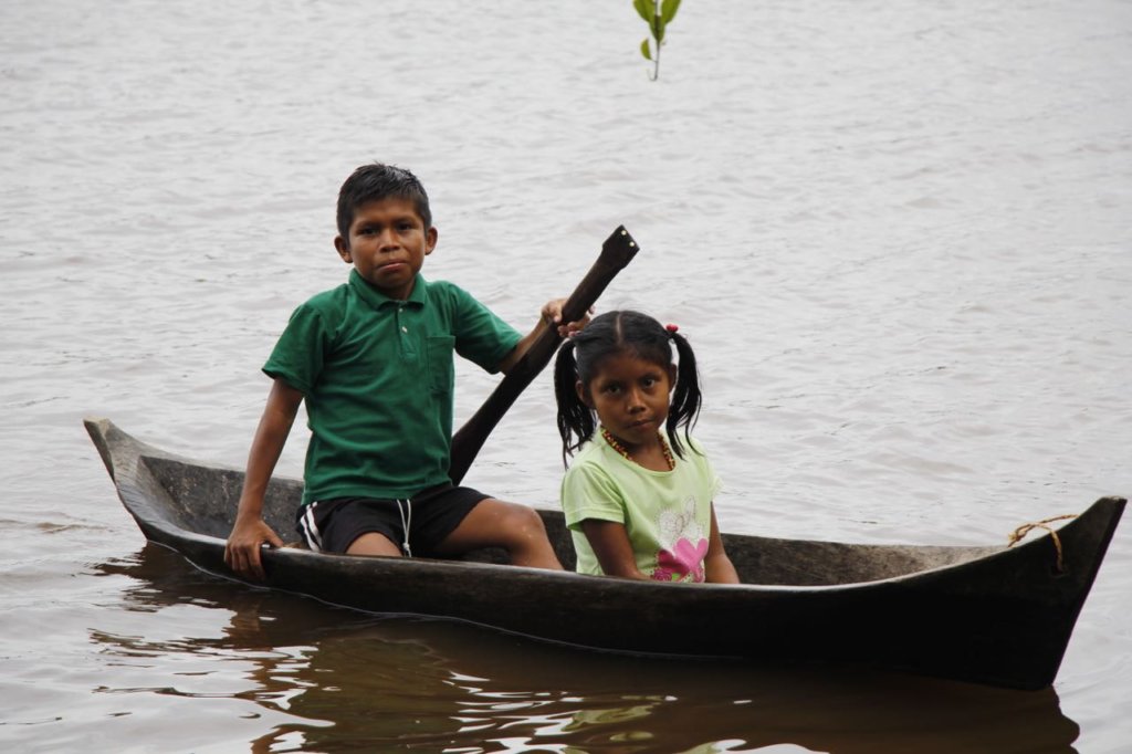 A boy brings his sister to clinic from far upriver