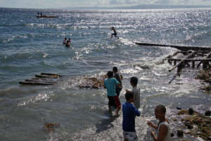 A man leaps from shore to assist the crew.
