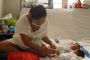A young mother with her twin newborns