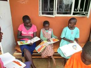 Teenage girl (in pink) helping the kids 'read'