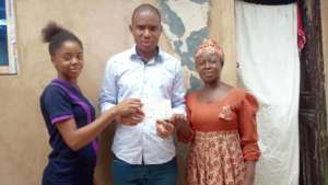 Emeke presents the cheque to Naomi and her mom.