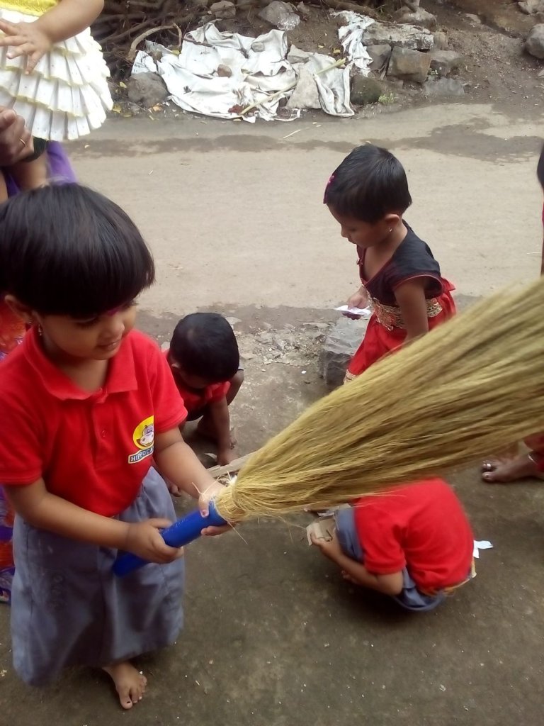 A child using a broomstick to clean the premise