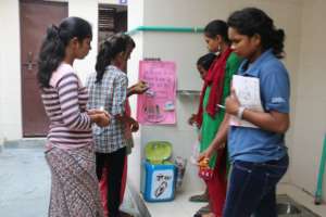 Girls installing disposal bin in community toilet