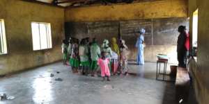 Kids talking to the teacher in an empty classroom