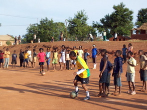 Sarita, in yellow, shows young players how to control the ball w
