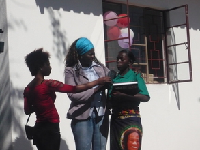 Milca, last year's top student, reads a poem with media present.