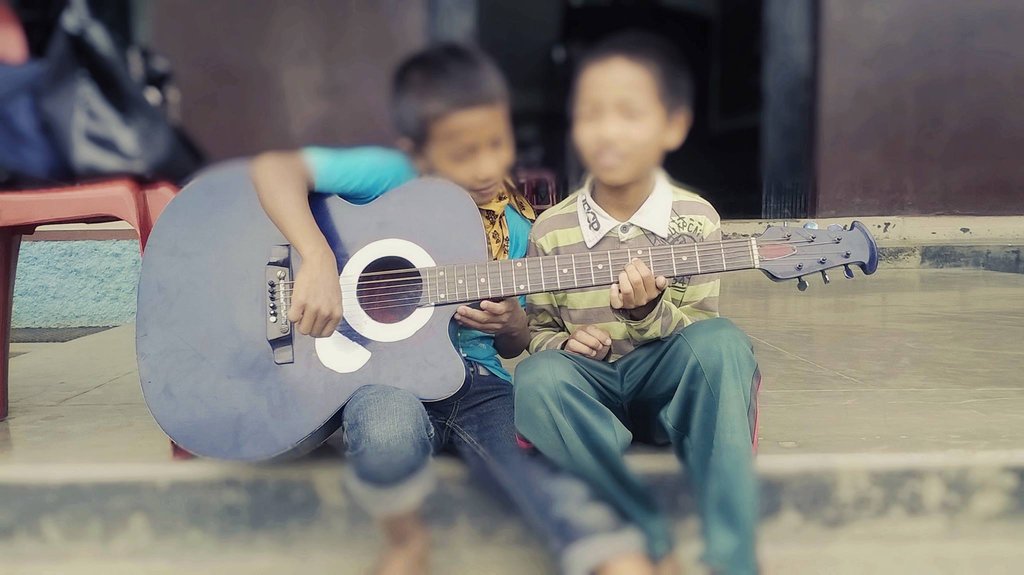 Children practicing guitar lessons