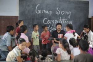 Akhu teaching music to the children
