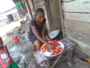 Itsa sells tomatoes in front of her house