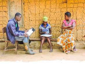 Patience (center) screens her neighbor for Ebola.