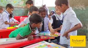 A young girl teaching her fellow classmates ludo!