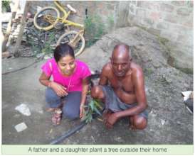 Daughter and father happily plant sapling together