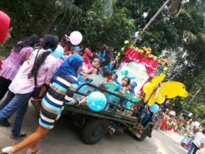 Moms pushing decorative floats with their children