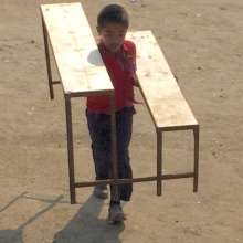 Student helping carry in new desk and bench sets
