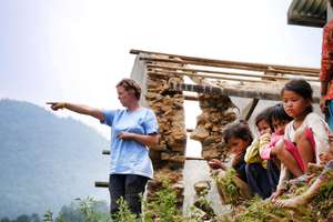 Architect Ruth with kids and damaged school behind