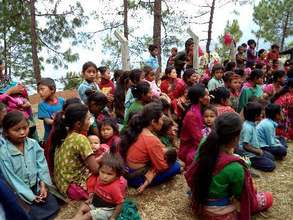 Mothers and children wait for a mid-day meal
