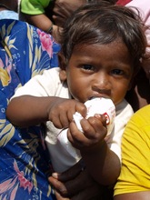 Baby clutching a milk packet donated by Care&Share