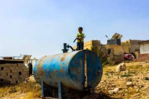 Playing atop a rusty water container