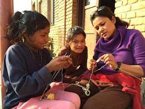 Sunita (L) learns to knit from Uma Auntie
