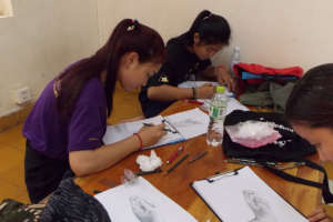Students practice drawing a dancer's hand