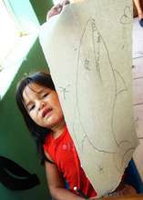Anna proudly rises her memee0a (fish) drawing