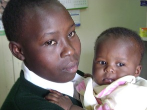 Sheila in school uniform holds her baby