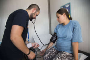 A health worker checks Roumatsh's blood pressure