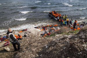 Vaios helping refugees climb from their raft