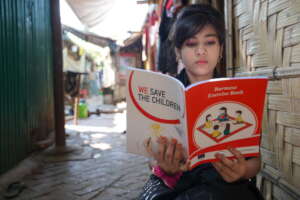 Nuri*, 15, reading a lesson book in the camp.