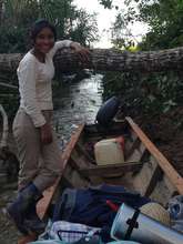 Aracely taking canoe up shady jungle rivelet