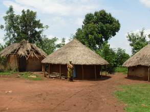 Old women next to house group built for her.