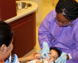 Joy cleans and checks Mateo's teeth