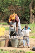A mother and child work side-by-side in the garden