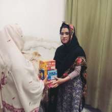 Kainat handing over biscuits and food to a widow