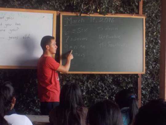 Senior student teaching English to young ones