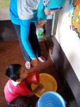Kindergarten teacher assists student wash hands