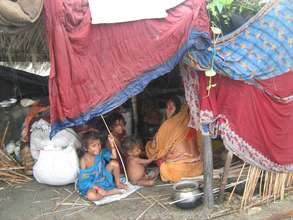A family takes shelter under a tarpulin