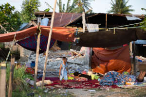 A boy walks outside his damaged house in Palu.