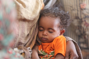 child sleeps on his mother's lap in Atbara, Sudan