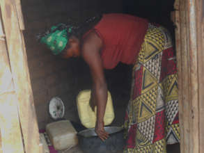 Hekima's mother pours water into a cooking pot.